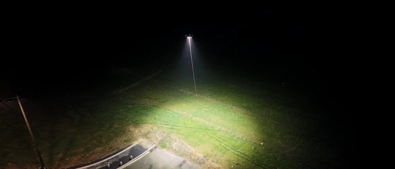 Kabelgebundene Drohne beleuchtet nachts ein Feld